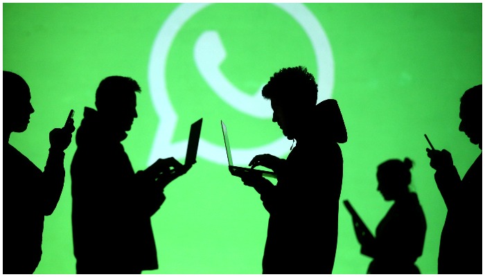 Silhouettes of laptop and mobile device users are seen next to a screen projection of Whatsapp logo in this picture illustration taken March 28, 2018. — Reuters/File