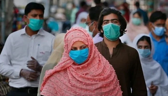 People waering masks walk in a market in Pakistan. — Reuters/File