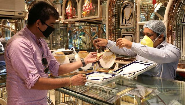 A salesman shows gold necklaces to a customer at a jewellery showroom in Kolkata, India, August 10, 2020. — Reuters/File