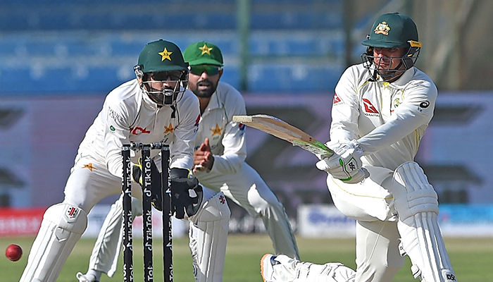 Australia´s Usman Khawaja (R) plays a shot as Pakistan´s wicketkeeper Mohammad Rizwan watches during the first day of the second Test cricket match between Pakistan and Australia at the National Cricket Stadium in Karachi on March 12, 2022. — AFP