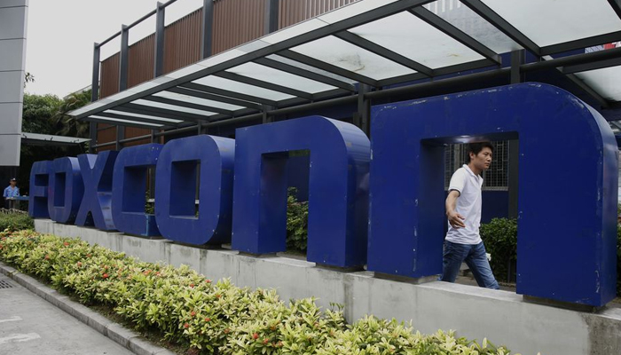 A man walks past a company logo at the entrance to a Foxconn factory in the township of Longhua in the southern Guangdong province on May 27, 2010. — Reuters