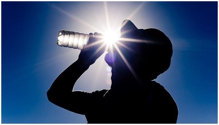 Silhouette of a man drinking water from a bottle is seen against the shining sun. Photo: AFP
