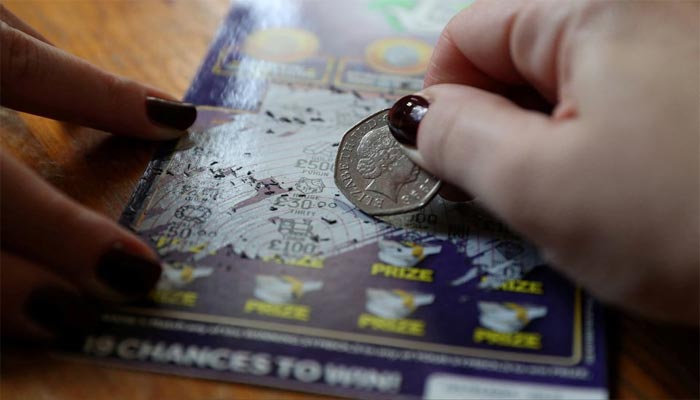 A fifty pence piece is used to play a National Lottery scratch card in Harpenden, Britain, November 19, 2017. REUTERS/Peter Cziborra/File Photo