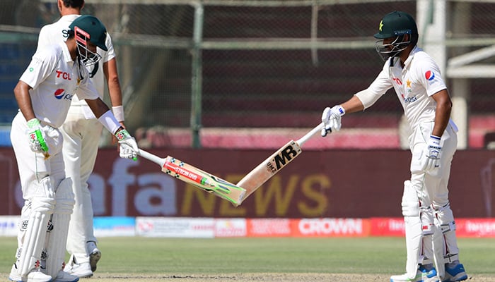 Pakistans captain Babar Azam (L) and Pakistans Abdullah Shafique (R) gesture during the fourth day of the second Test cricket match between Pakistan and Australia at the National Cricket Stadium in Karachi on March 15, 2022. — AFP