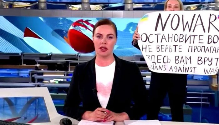Marina Ovsyannikova, seorang karyawan Channel One menggelar protes di udara dengan mengangkat tanda anti-perang di belakang presenter studio.  — Reuters