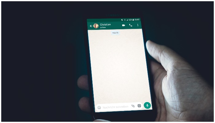 Image showing a person holding their cellphone showing a WhatsApp screen — Christian Wiediger / Unsplash