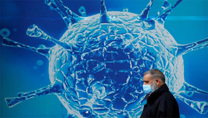 A man wearing a protective face mask walks past an illustration of a virus outside a regional science centre amid the coronavirus disease (COVID-19) outbreak, in Oldham, Britain August 3, 2020. Photo: Reuters