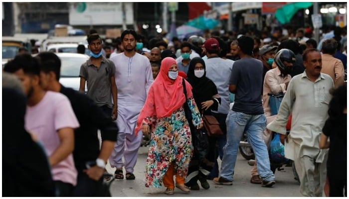 Women wearing protective face masks walk amid the rush of people along a road in Karachi. Photo: Reuters/ file