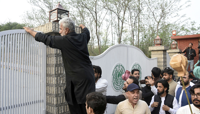 Pekerja PTI mencoba menerobos masuk ke Rumah Sindh setelah merobohkan gerbangnya, di sini di Islamabad pada 18 Maret 2022. — Kantor Berita ONLINE