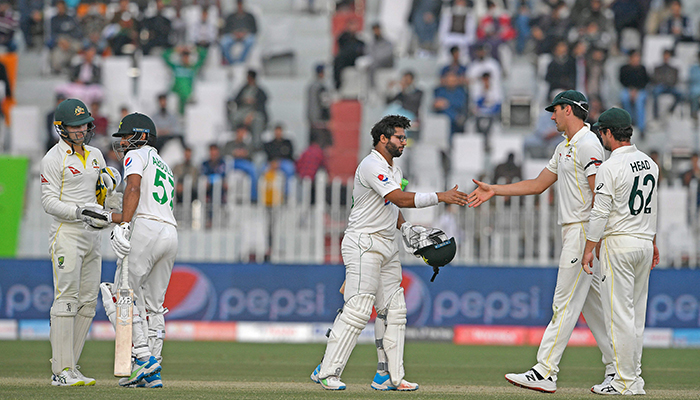 Pakistans Imam-ul-Haq (3R) shakes hands with Australias captain Pat Cummins (2R) and Pakistans Abdullah Shafique (2L) shakes hands with Australias Alex Carey (L) after a draw in the first Test cricket match between Pakistan and Australia at the Rawalpindi Cricket Stadium in Rawalpindi on March 8, 2022. — AFP
