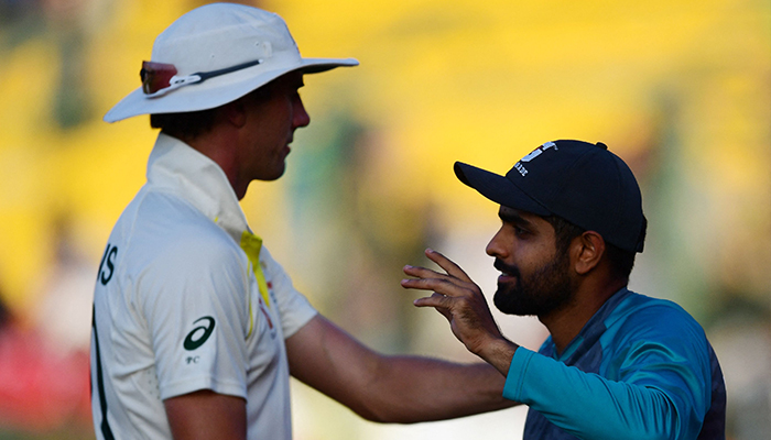 Australias captain Pat Cummins (L) and Pakistans captain Babar Azam interact after a draw in the fifth and final day of the second Test cricket match between Pakistan and Australia at the National Cricket Stadium in Karachi on March 16, 2022. — AFP