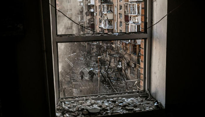Ukrainian servicemen are seen through a building window as they carry the remains o a missile after shelling in a residential area in Kyiv on March 18, 2022, as Russian troops try to encircle the Ukrainian capital as part of their slow-moving offensive. AFP