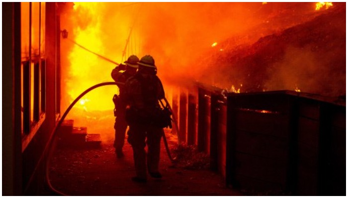 Firefighters try to contain the flames engulfing a building. Photo: AFP/ file
