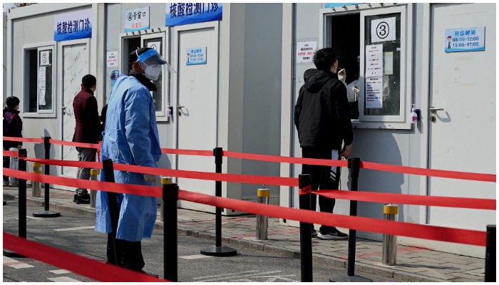 A health worker gets a swab sample on a woman to be tested for Covid-19 coronavirus at a swab collection site in Beijing on March 20, 2022. — Noel Celis / AFP