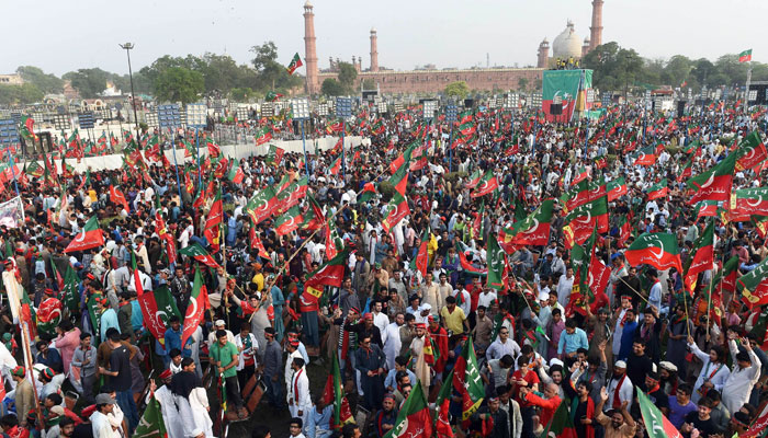 Supporters gesture and wave PTI flags as they attend rally in Lahore. — AFP/File