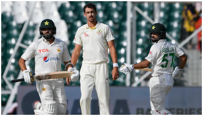 Abdullah Shafique and Azhar Ali score a run while an Aussie bowler stands near the pitch. Photo: AFP/ file