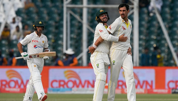 Australias captain Pat Cummins (R) celebrates with a teammate after taking the wicket of Pakistans Naseem Shah (L) during the third day of the third cricket Test match between Pakistan and Australia at the Gaddafi Cricket Stadium in Lahore on March 23, 2022. — AFP