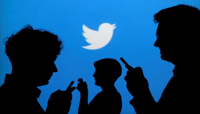 People holding mobile phones are silhouetted against a backdrop projected with the Twitter logo in this illustration picture taken in Warsaw September 27, 2013. —Reuters