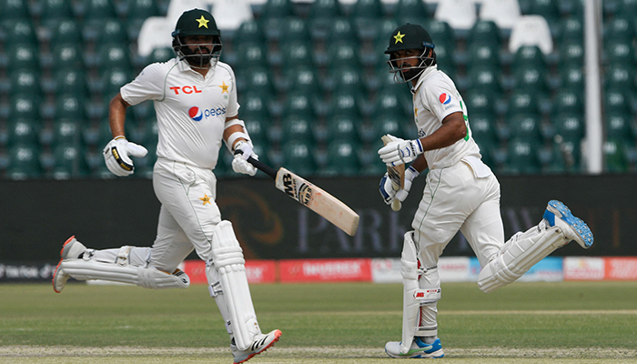 Pakistans Azhar Ali (L) and Abdullah Shafique take a run during the third day of the third cricket Test match between Pakistan and Australia at the Gaddafi Cricket Stadium in Lahore on March 23, 2022. — AFP