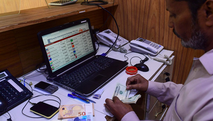 A foreign currency dealer counts US dollar bills at a shop in Karachi on February 25, 2022. — AFP/File