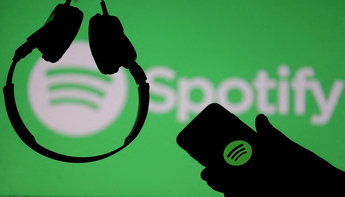 A smartphone and a headset are seen in front of a screen projection of Spotify logo, in this picture illustration taken April 1, 2018.—Reuters