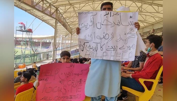 Man holding placard during Pakistan vs Australia 2nd Test match. — Twitter/@iihtishamm