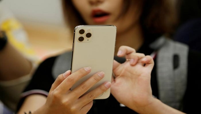 A woman holds an iPhone 11 Pro Max while giving a live broadcast after it went on sale at the Apple Store in Beijing, China, September 20, 2019.—Reuters