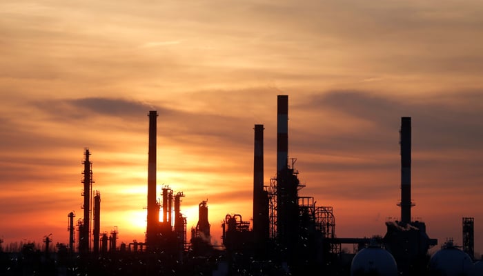 The sun sets behind the chimneys of the Total Grandpuits oil refinery southeast of Paris, France, on February 29, 2016. — Reuters