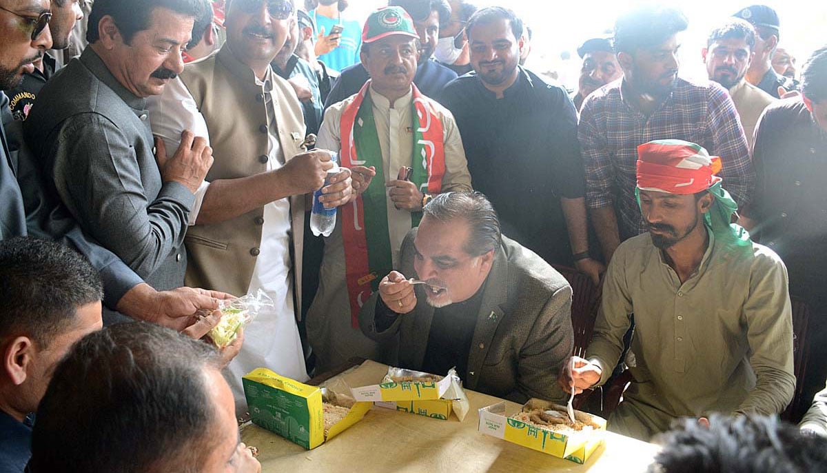 Governor Sindh Imran Ismail eating lunch hosted by PTI workers. — APP