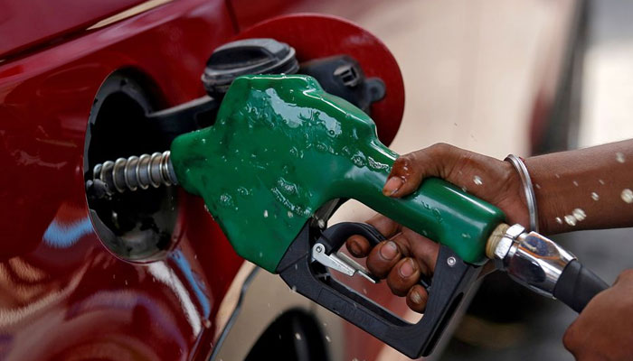 A worker holds a nozzle to pump petrol into a vehicle at a fuel station in Mumbai, India, May 21, 2018. Reuters/File