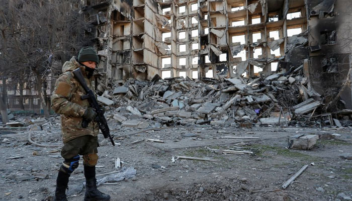 A service member of pro-Russian troops stands near an apartment building destroyed in the course of Ukraine-Russia conflict in the besieged southern port city of Mariupol, Ukraine March 28, 2022. REUTERS/Alexander Ermochenko