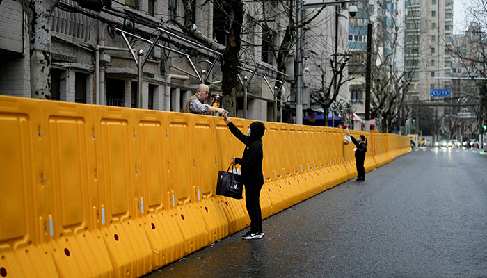 People pass food to residents over the barriers of an area under lockdown, amid the coronavirus disease (COVID-19) pandemic, in Shanghai, China March 25, 2022. — Reuters