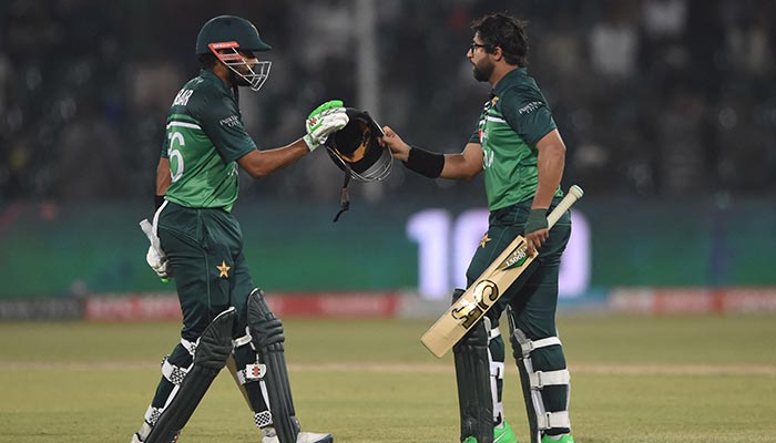 Imam-ul-Haq Pakistan (kanan) merayakan dengan rekan setimnya Babar Azam (kiri) setelah mencetak satu abad (100 run) selama pertandingan kriket internasional satu hari (ODI) kedua antara Pakistan dan Australia di Stadion Kriket Gaddafi di Lahore pada Maret 31, 2022. — AFP