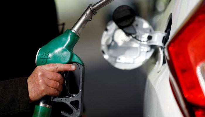 A man holds a fuel nozzle at a petrol station. — Reuters/File