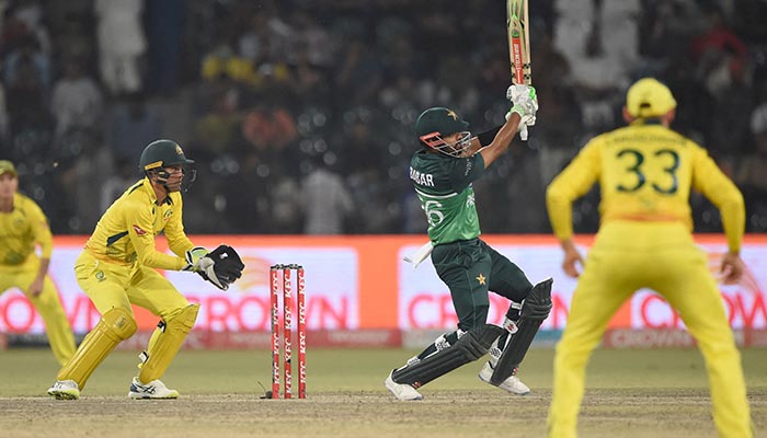 Pakistans Babar Azam (C) is watched by Australias wicketkeeper Alex Carey (L) as he plays a shot during the second one-day international (ODI) cricket match between Pakistan and Australia at the Gaddafi Cricket Stadium in Lahore on March 31, 2022. — AFP