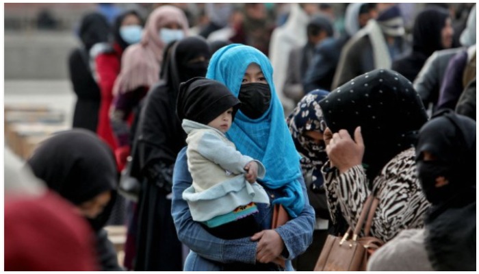 An Afghan woman holds her child as she and others wait to receive a package being distributed by a Turkish humanitarian aid group at a distribution centre in Kabul, Afghanistan, December 15, 2021. — Reuters/Ali Khara