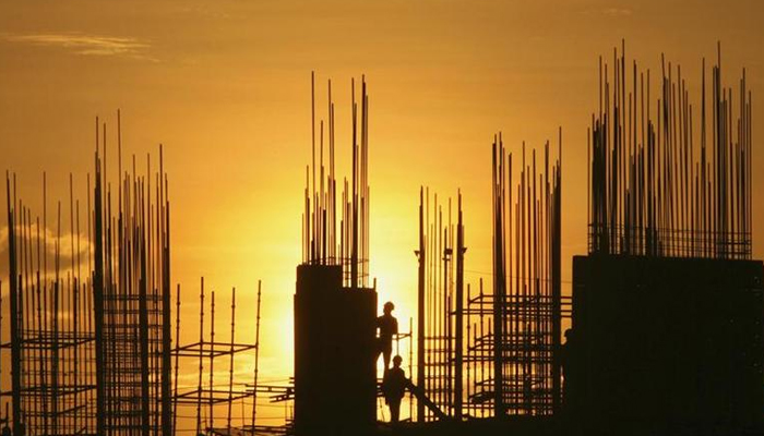 Labourers are silhouetted against the setting sun as they work at the construction site of a residential building in Hyderabad on October 5, 2012. Reuters/File