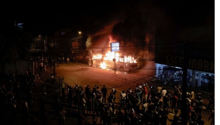 Demonstran berdiri di dekat sebuah bus yang dibakar di puncak jalan menuju kediaman Presiden Sri Lanka Gotabaya Rajapaksas selama protes terhadapnya karena banyak bagian negara yang dilanda krisis menghadapi hingga 13 jam tanpa listrik karena kekurangan pasokan asing. mata uang untuk mengimpor bahan bakar, di Kolombo, Sri Lanka 31 Maret 2022. —Reuters