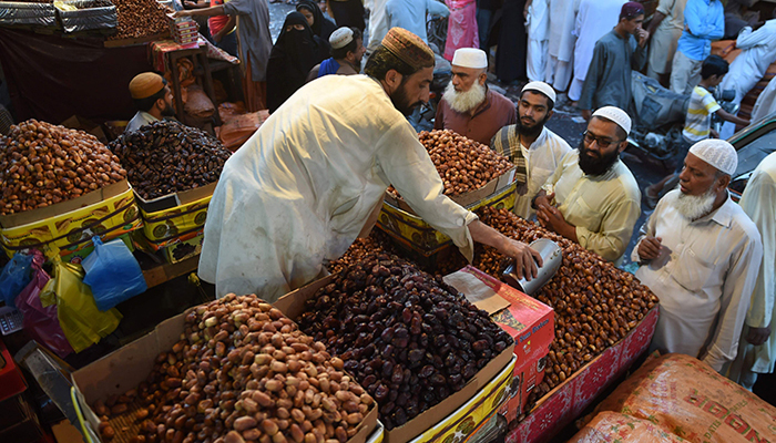 People buy dates from a shop at a market in Karachi on the eve of Ramadan. ─ AFP/File