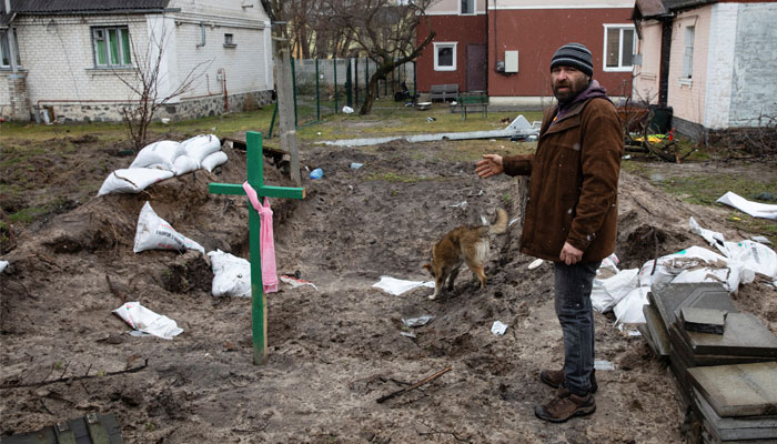 A man stands next to a grave, amid Russias invasion on Ukraine, in Bucha, Ukraine April 3, 2022. — Reuters