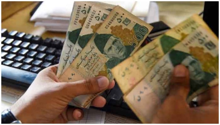 A currency dealer is counting Rs500 notes. — AFP/ file