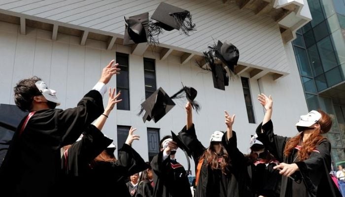 Graduates wearing Guy Fawkes masks throw their hats as they pose for their photo after a graduation ceremony at the Chinese University of Hong Kong in Hong Kong, November 7. Reuters