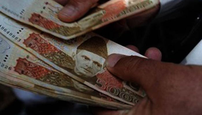 A currency dealer counts Rs5,000 notes. — AFP/File