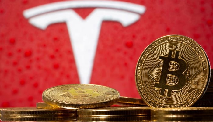 Representations of the virtual currency bitcoin are seen in front of the Tesla logo in this illustration taken, on February 9, 2021. — Reuters