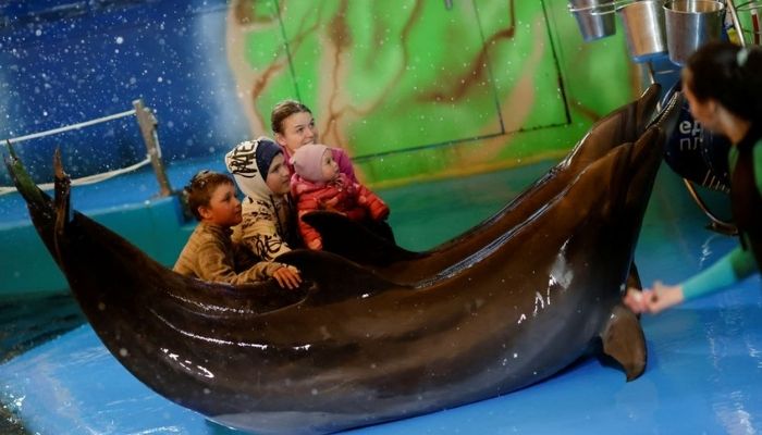 A Ukrainian family, who has fled Kherson amid the Russian invasion, poses for a photograph after a dolphin show at a hotel, in Odesa, Ukraine April 9, 2022. Picture taken April 9, 2022. Reuters