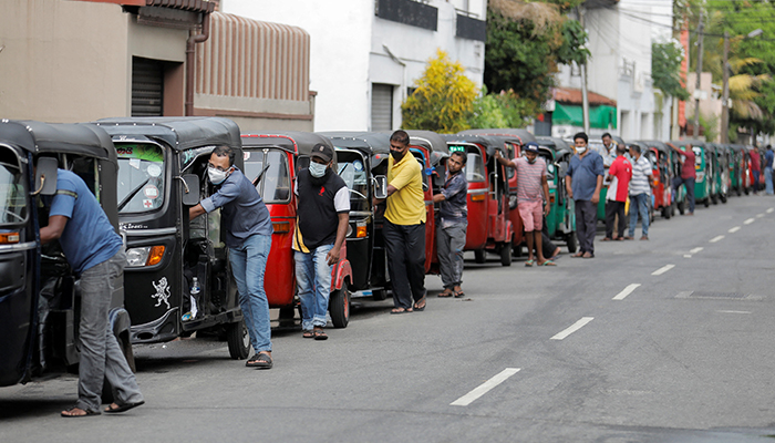 Drivers push their three-wheelers while waiting in a line to buy petrol at a Ceylon Ceypetco fuel station on a main road, amid the countrys economic crisis in Colombo, Sri Lanka, April 12, 2022. — Reuters