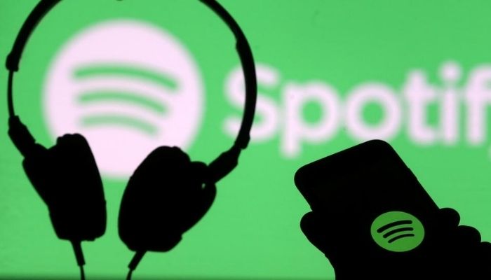 A smartphone and a headset are seen in front of a screen projection of the Spotify logo, in this picture illustration taken April 1, 2018. Reuters