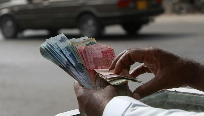A money changer counts Pakistani Rupee (PKR) notes in Karachi, on September 23, 2009. — Reuters