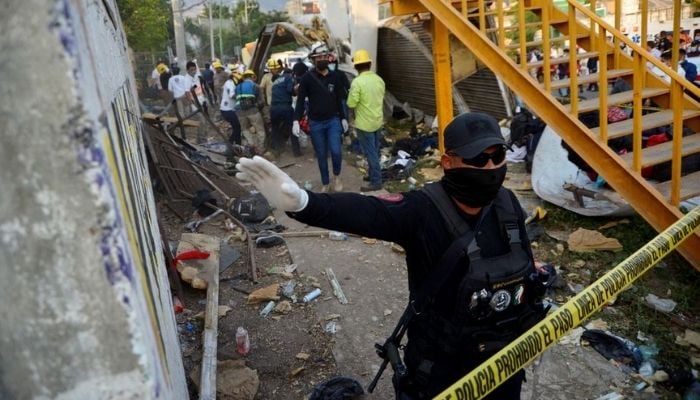 A police officer raises his arm to block photographers to to avoid taking pictures at the site of a trailer accident that left at least 49 people dead, most of them migrants from Central America, in Tuxtla Gutierrez, in Chiapas state, Mexico December 9, 2021. Reuters