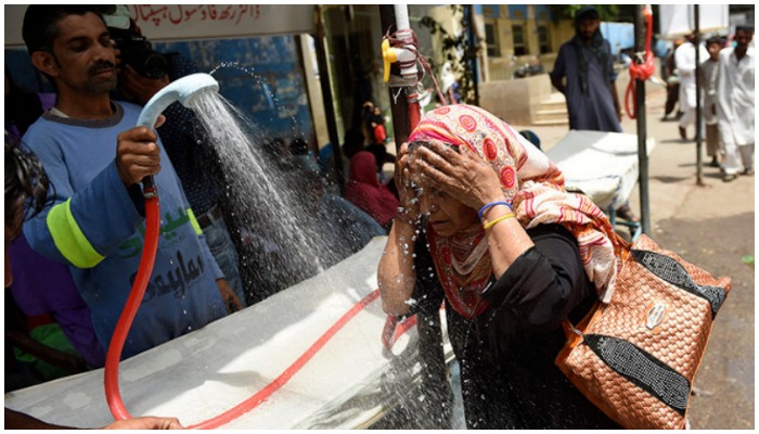 In this file photo, a volunteer showers a woman with water during a heatwave in Karachi. — AFP